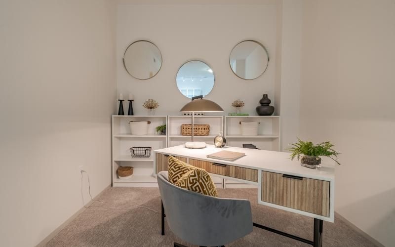 a room with a desk and chairs and mirrors